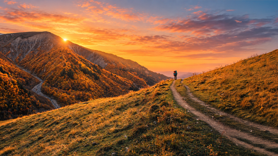 Wanderperson auf einem Bergpfad im Abendlicht